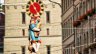 Bunte Brunnenfigur eines Dudelsackpfeifers mit Gans, der Pfeiferbrunnen an der Berner Spitalgasse, davor das Zifferblatt des Käfigturms und Altstadtfassaden mit roten Blumenkästen an den Fenstern. Umgebung der Praxis Spitalgasse.